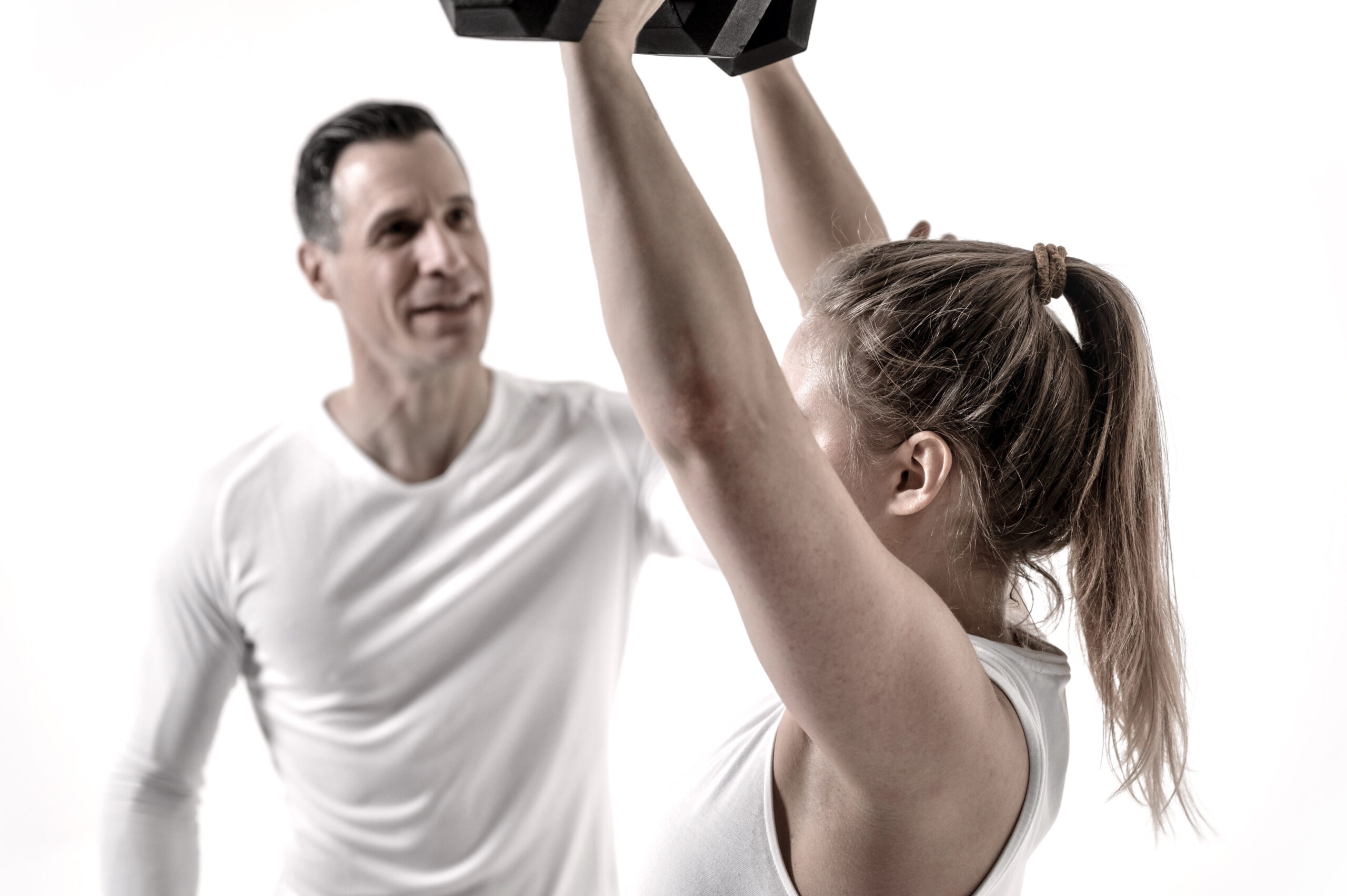 Ein Personaltrainer korrigiert die Ausführung einer uebung seines Klienten.